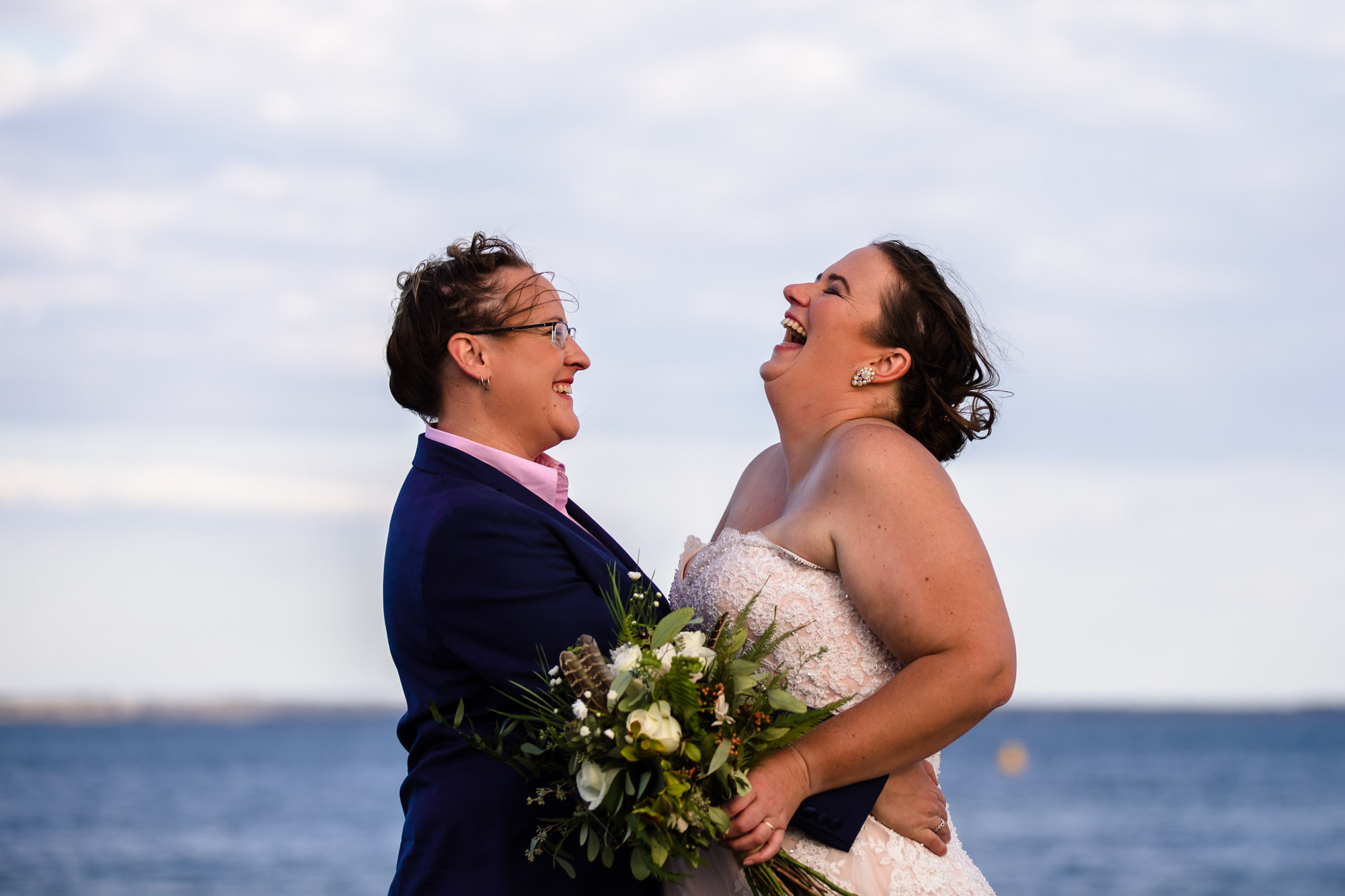 two brides laughing while walking along Avalon Beach 
