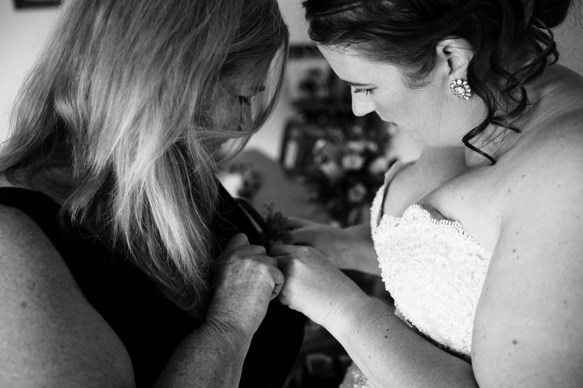 bride helping her mother put on corsage