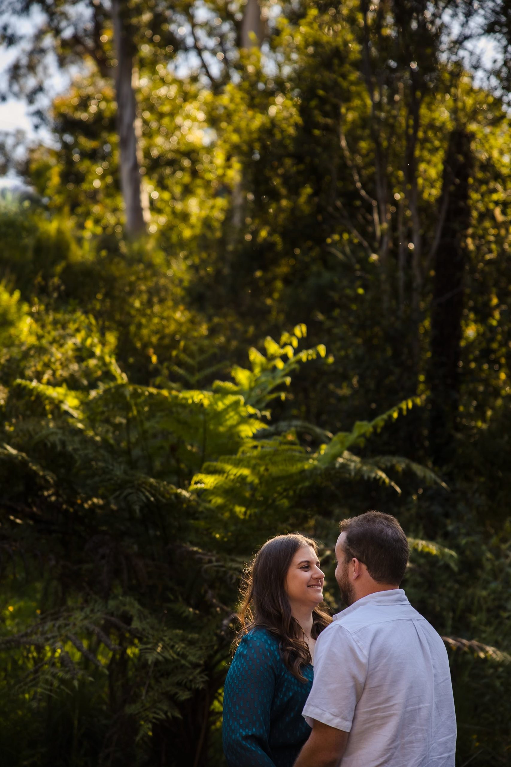 couple smiling at each other with belgrave ferns in the background